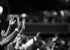 Black and white image of audience with hands raised, capturing concert energy.