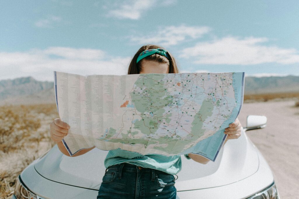 pexels-photo-3935702-3935702 A woman holds a map while traveling through the scenic desert of California, USA.